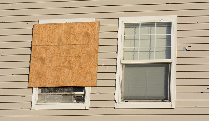 Boarded-up windows in a hail damaged house